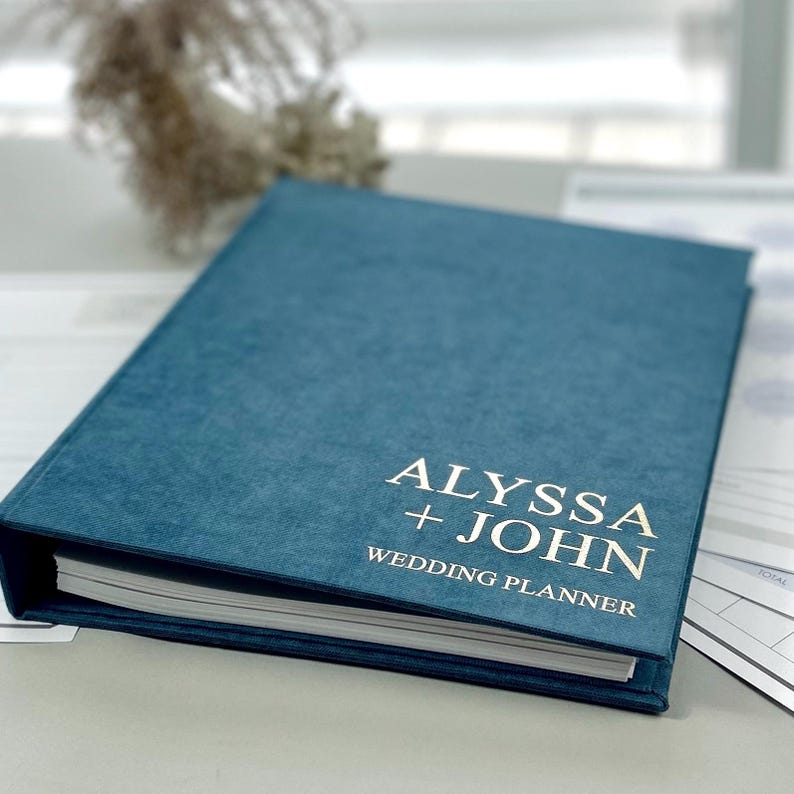 Personalized wedding planner binder to organize your entire wedding in one place — includes all checklists, timelines, budget sheets, and vendor contract sections. Fully customizable cover and spine colors with your names, wedding date, or custom text. Perfect keepsake for brides and wedding planners to stay organized from engagement to wedding day.