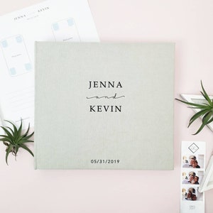 May include: A light gray linen wedding guest book with the names Jenna and Kevin and the date 05/31/2019 printed in black.