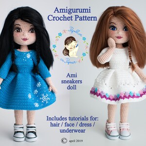 May include: Two crocheted dolls wearing dresses and sneakers. The doll on the left has black hair and a blue dress with snowflakes. The doll on the right has brown hair and a white dress with a purple, pink, and blue trim. The dolls are part of an amigurumi crochet pattern.