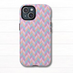 May include: A smartphone case featuring a repeating herringbone pattern in shades of light pink, soft blue, and muted orange. The case has a black camera cutout area at the top left corner and covers the back of the device with a consistent geometric design.
