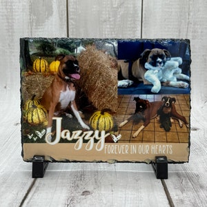 May include: A black slate photo memorial with a collage of three photos of a brown and white boxer dog. The slate has a tan background with the text "Jazzy" in white cursive font and the text "Forever in our hearts" in white sans-serif font.