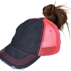 May include: A black and pink distressed baseball cap with a mesh back. The cap has a ponytail hole in the back.