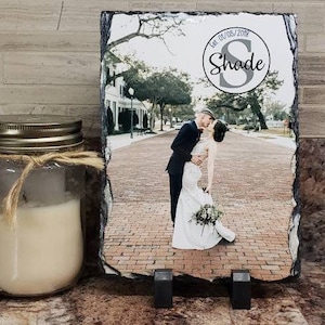 May include: A black slate plaque with a photo of a couple kissing. The plaque has a white circle with the text "Est. 01/05/2018 Shade" in black.