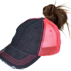 May include: A black and pink distressed baseball cap with a mesh back. The cap has a ponytail hole in the back.