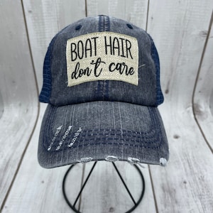May include: A blue and gray distressed baseball cap with a white patch that reads "BOAT HAIR don't care".