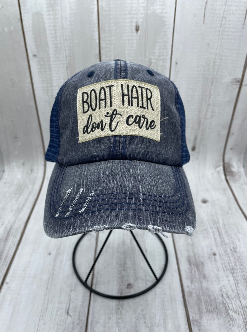 May include: A blue and gray distressed baseball cap with a white patch that reads "BOAT HAIR don't care".