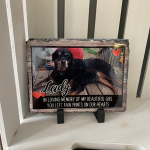 May include: A black and brown dog memorial slate with a photo of the dog and the text "Lady" in cursive. The slate also includes the text "In loving memory of my beautiful girl you left paw prints on our hearts".