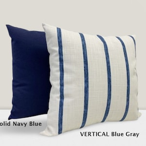 Peut inclure: Deux coussins décoratifs, l'un bleu marine uni et l'autre blanc à rayures verticales bleu et gris. Les coussins sont étiquetés "Solid Navy Blue" et "VERTICAL Blue Gray".