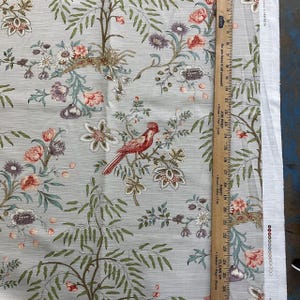 May include: A light gray fabric with a repeating pattern of red birds, green leaves, and pink and white flowers.