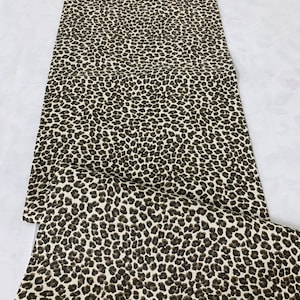 May include: A white fabric with a brown leopard print pattern.