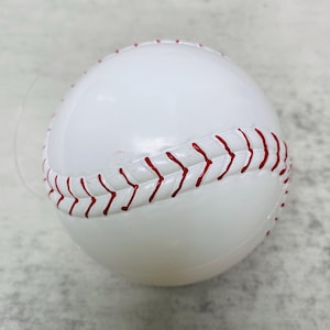May include: A white baseball with red stitching. The ball is a toy or decoration.
