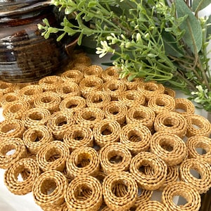 May include: A woven, round, straw-like coaster with a pattern of circles. The coaster is light brown in colour and has a natural, rustic look.