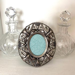 Marco de fotos floral ovalado vintage, estilo Art Nouveau, de metal fundido, 10 x 8 cm, independiente, con iris estilizado, pequeño, plateado.