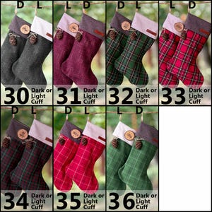 May include: A collection of seven pairs of Christmas stockings, each featuring a wooden name tag and a small pinecone accent. The stockings come in various textures and patterns, including solid gray, maroon, green plaid, and red plaid designs.