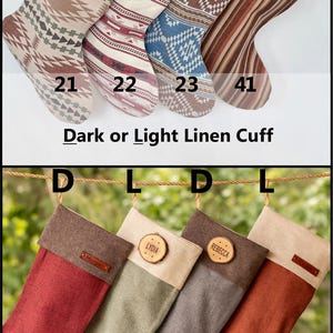 May include: Eight Christmas stockings with numbered labels 21, 22, 23, 41, 25, 26, 27, and 28. The stockings feature various patterns, solid colors, and personalized wooden or leather tags with names like Caroline, Alex, Brutus, Wyatt, Morgan, Lydia, and Rebecca. Text includes Dark or Light Linen Cuff.