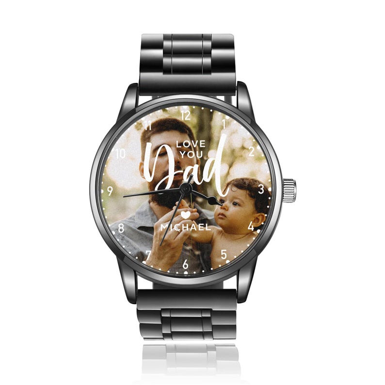 K&ouml;nnte beinhalten: Schwarze Armbanduhr mit einem Foto von Vater und Kind auf dem Zifferblatt. Auf dem Zifferblatt steht in wei&szlig;er Schrift "Love You Dad". Die Uhr hat ein schwarzes Metallarmband und eine silberne Krone.