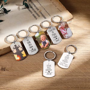 May include: A collection of personalized metal keychains with various designs and text. Some keychains feature photos, while others have phrases like "I love you Mom" and "We love you Daddy." The keychains are silver and have a rectangular shape.