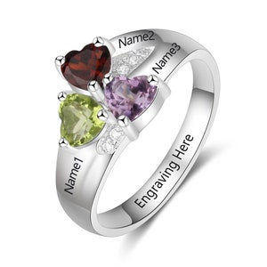 May include: Silver ring with three heart-shaped gemstones: green, purple, and red. The ring has the words "Name1", "Name2", and "Name3" engraved on it, along with the text "Engraving Here".