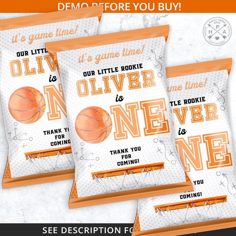 Peut inclure: Trois sacs de cadeaux de f&ecirc;te sur le th&egrave;me du basket-ball. Les sacs sont blancs et orange, avec le texte "it's game time!" et "OUR LITTLE ROOKIE OLIVER is ONE". Chaque sac dit &eacute;galement "THANK YOU FOR COMING!" et a un graphique de basket-ball.