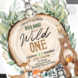 May include: A woodland-themed first birthday party invitation with a brown wooden circle background. The text "Join us to celebrate Roland is a Wild One" is written in green and gold lettering. The date and time of the party are listed below, along with the address. The invitation features illustrations of a rabbit, owl, bear, deer, fox, and raccoon.