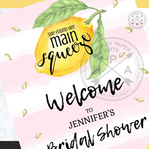 May include: A pink and white striped background with a yellow lemon and green leaves. The text "She found her main squeeze" is written in black cursive. The text "Welcome to Jennifer's Bridal Shower" is written in black cursive.