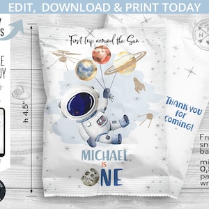 May include: A white and blue astronaut-themed party favor bag with a cartoon astronaut holding balloons shaped like planets. The bag is decorated with gold glitter stars and the text "First trip around the Sun". The bag is 4.5 inches tall and is designed to hold a small snack bag. The text "Michael is One" is printed on the front of the bag.