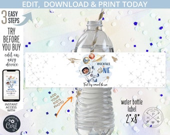 May include: A printable water bottle label with a space theme. The label features a cartoon astronaut holding balloons with planets, a white background with silver stars, and the text "Michael is One" and "First trip around the sun".
