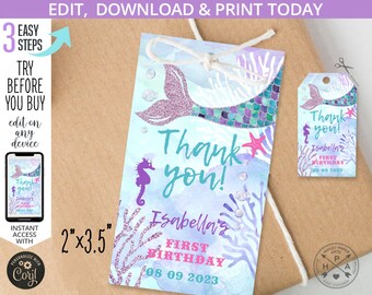 May include: A mermaid tail with purple and green glitter scales, a starfish, and a seahorse on a blue watercolor background. The text "Thank you! Isabella's First Birthday 08 09 2023" is printed on the tag. The tag is 2 inches by 3.5 inches.
