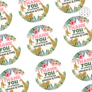 May include: Pink and green thank you stickers with gold glitter accents. The stickers feature a jungle theme with giraffes, monkeys, and tropical leaves. The text on the stickers reads "Thank You for swinging by Johnatan & Emily".