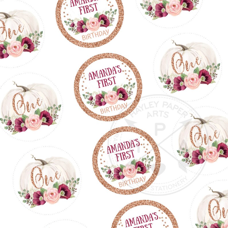 May include: A set of round, white pumpkin-shaped stickers with gold glitter accents. The stickers feature a floral design with pink and burgundy flowers and greenery. The text "One" is written in gold glitter on the pumpkins. The stickers also feature a circle with gold glitter and the text "Amanda's First Birthday".