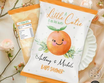 Könnte beinhalten: Ein weißer Chip-Beutel mit einer orangefarbenen und grünen Illustration einer Orange mit einem lächelnden Gesicht. Der Text "A Little Cutie is on the way!" befindet sich oben auf dem Beutel. Der Text "Anthony & Michele Baby Shower" befindet sich unten auf dem Beutel.