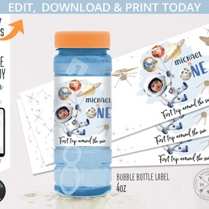 May include: A blue and white bubble bottle label with a space theme. The label features a cartoon astronaut holding balloons with planets, a moon, and stars. The text on the label reads "Michael is One" and "First trip around the sun".