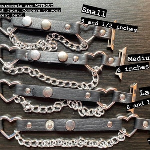 May include: Four black leather Apple Watch bands with silver heart-shaped clasps and silver chain accents. The bands are shown in different sizes: small (5 1/2 inches), medium (6 inches), large (6 1/4 inches), and XL (7 inches).