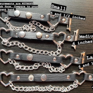 May include: Four black leather Apple Watch bands with silver heart-shaped clasps and silver chain accents. The bands are shown in different sizes: small (5 1/2 inches), medium (6 inches), large (6 1/4 inches), and XL (7 inches).