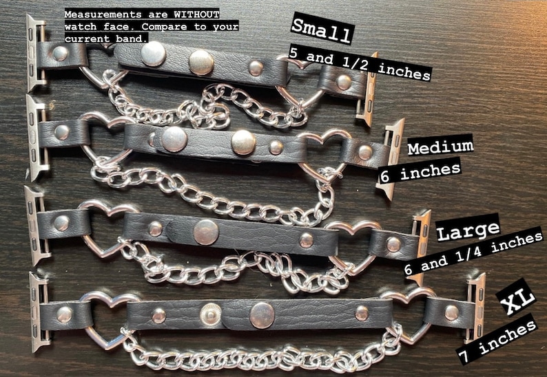 May include: Four black leather Apple Watch bands with silver heart-shaped clasps and silver chain accents. The bands are shown in different sizes: small (5 1/2 inches), medium (6 inches), large (6 1/4 inches), and XL (7 inches).