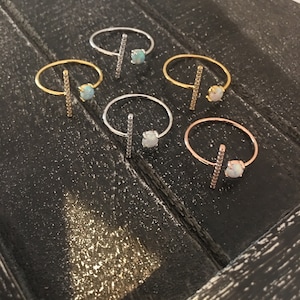 May include: Six rings with a single opal stone and a bar of cubic zirconia stones. The rings are in silver, gold, and rose gold.