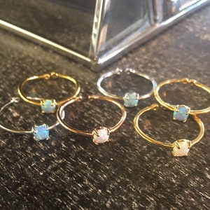 May include: Five opal rings in different metal finishes: gold, rose gold, and silver. Each ring features a small, round opal gemstone.