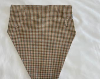 May include: A brown, blue, and beige plaid fabric triangle with a pointed bottom. The fabric is sewn together with a blue thread.