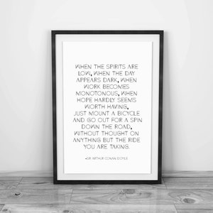 May include: A framed print with a black border, featuring a quote by Sir Arthur Conan Doyle. The quote is in black text on a white background. The print is leaning against a wall on a wooden floor.