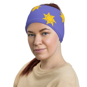 May include: A purple headband with three yellow sun designs. The headband is made of a soft, stretchy fabric.