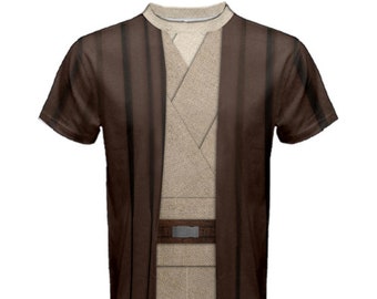 Puede incluir: Una camiseta marrón y beige con un diseño impreso de una túnica Jedi. La túnica tiene una capa exterior marrón y una capa interior beige con un cinturón marrón.