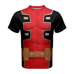 Puede incluir: Una camiseta de manga corta negra y roja con un estampado gráfico del torso de un superhéroe. El diseño presenta un pecho rojo con detalles negros y marrones, y un cinturón marrón con hebillas plateadas.