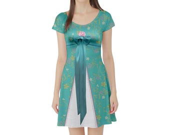 以下が含まれることがあります： 黄色と紫の花柄、ラウンドネック、ピンクの花のアクセントが付いた中央のティール色のリボンが特徴の、半袖のティール色のドレス。スカート部分には、レースのトリムが付いた白い三角形のパネルが挿入されています。