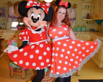 May include: A woman and a Minnie Mouse character wearing red and white polka dot dresses. The woman is wearing a red bow in her hair and yellow shoes. The Minnie Mouse character is wearing yellow shoes and a red bow on her head.
