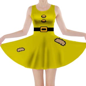 Puede incluir: Un vestido skater amarillo con un cinturón negro y dos botones amarillos. El vestido tiene dos parches marrones con costuras en la falda.
