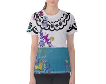 Könnte beinhalten: Weißes T-Shirt mit einem farbenfrohen Design, das von einer Filmfigur inspiriert wurde. Der obere Teil hat einen schwarzen Spitzenbesatz und florale Akzente. Der untere Teil ist türkis mit dekorativen Elementen und dem Wort "Mirabel".