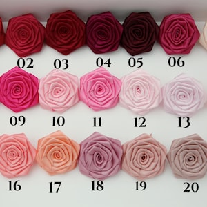 May include: A collection of 21 satin rose flower embellishments in various shades of red, pink, peach, and beige. Each flower is numbered from 01 to 21, offering a range of colors for crafting or decorative purposes.