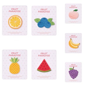 May include: Set of nine iron-on patches featuring various fruits, including a pineapple, watermelon, grapes, blueberries, a peach, a banana, and an orange. Each patch has the text "Fruit Paradise" on a pink background with white polka dots.