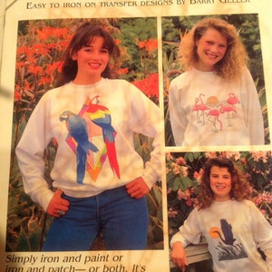 May include: A book cover with the title "Birds" and a subtitle "Easy to iron on transfer designs by Barry Geller". The cover features three women wearing white sweatshirts with colorful bird designs. The book includes new super graphic designs.