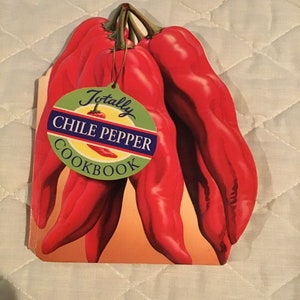 May include: A red and green cookbook with the title "Totally Chile Pepper Cookbook" and a picture of red chili peppers.